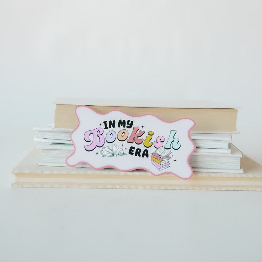 Stack of books with a decorative sign reading 'In my Bookish Era' on a white background