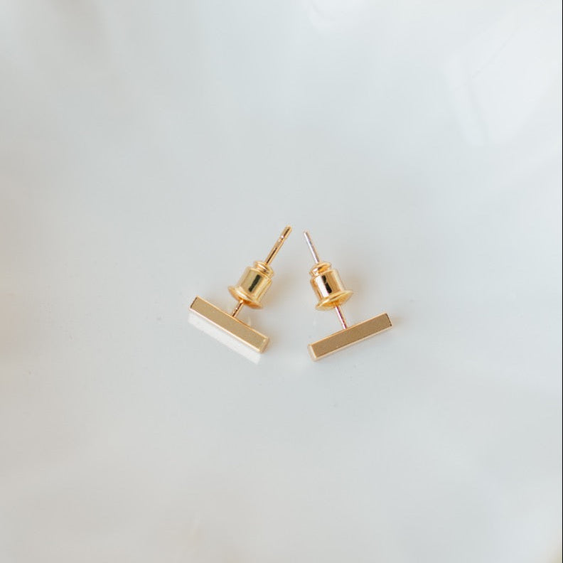 Gold earrings on a white dish